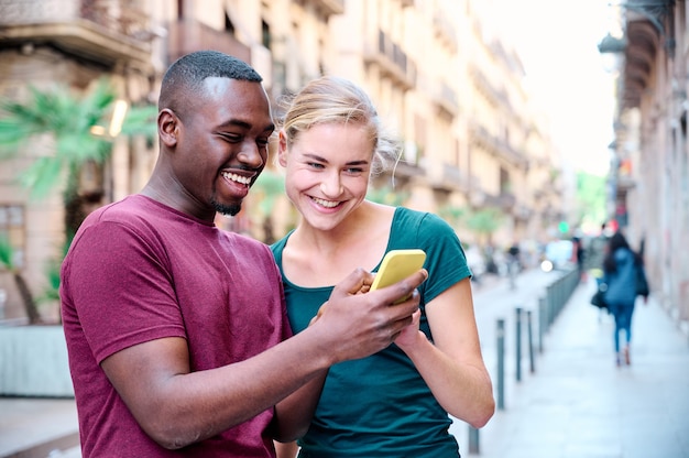 joven pareja interracial usando un teléfono móvil