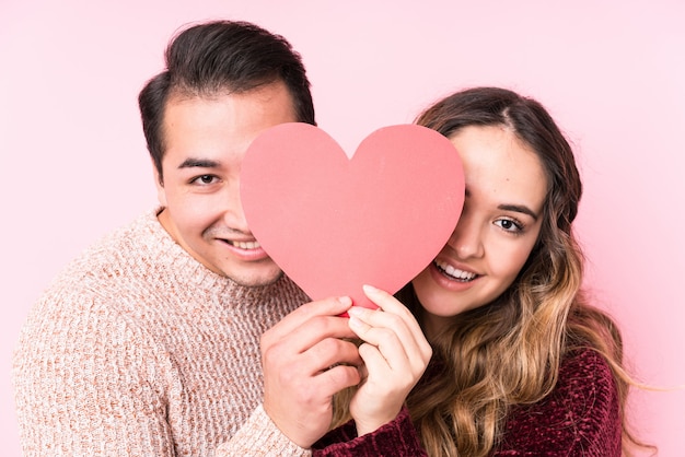 Joven pareja latina sosteniendo una pegatina de corazón