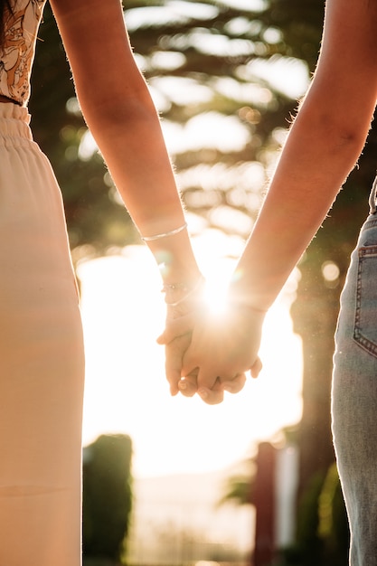 Joven pareja de lesbianas cogidos de la mano caminando al atardecer