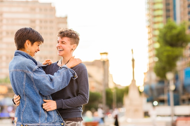 Joven pareja de lesbianas tomboy transexual andrógino no binario y una mujer hispana con pelo corto