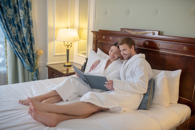 Una joven pareja leyendo un libro juntos en su dormitorio