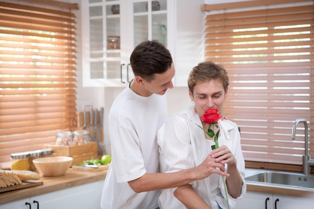 Una joven pareja LGBT celebra el día del amor con una copa de vino en la cocina de su casa