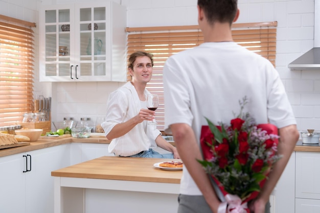 Una joven pareja LGBT celebra el día del amor con una copa de vino en la cocina de su casa