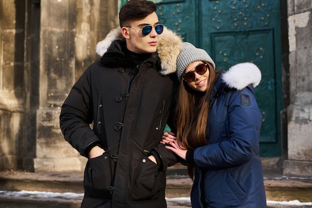 Una joven pareja de moda camina en la ciudad en Navidad.