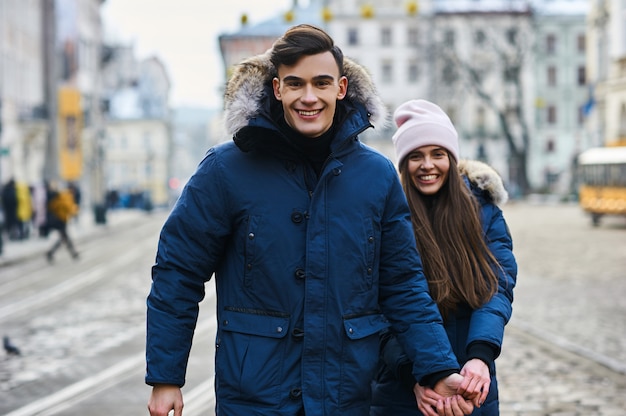 Una joven pareja de moda camina en la ciudad en Navidad.