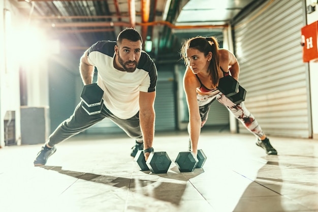 Foto joven pareja musculosa está haciendo ejercicio de fuerza en entrenamiento cruzado en el garaje.