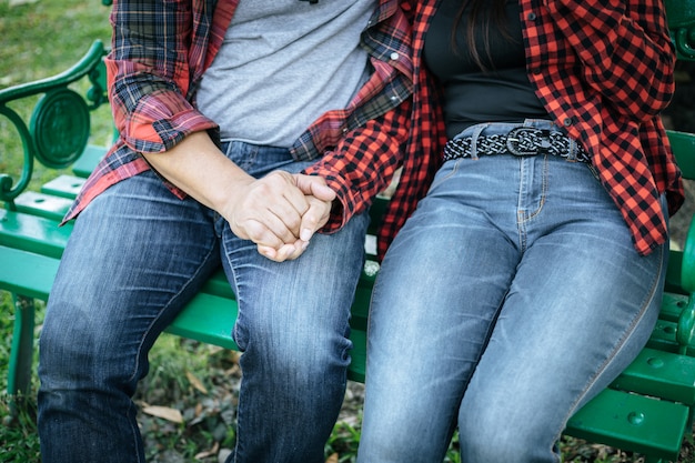 Joven pareja en la naturaleza sentado en el banco, hombres y mujeres juntos