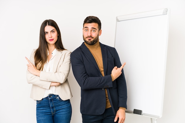 Joven pareja de negocios caucásicos aislados puntos de lado, está tratando de elegir entre dos opciones.