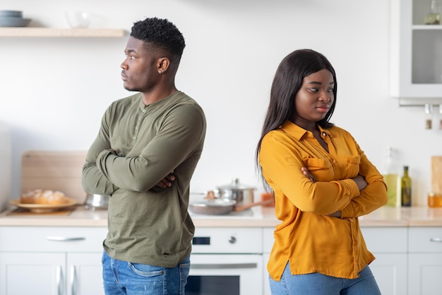 Joven pareja negra de pie espalda con espalda el uno al otro en la cocina