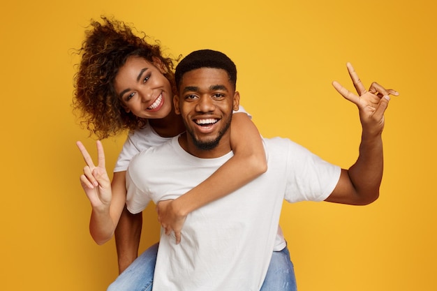 Foto una joven pareja negra viaja a lomos mostrando el gesto de 