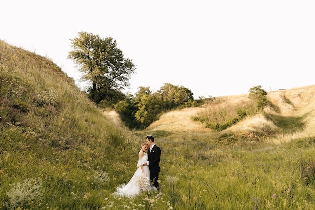 Foto joven pareja de novios abrazándose en el fondo de las colinas foto de alta calidad