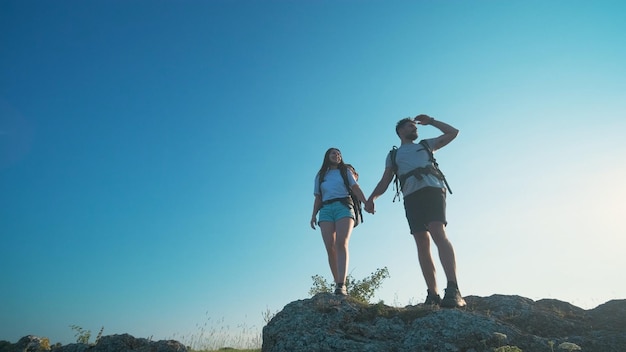 La joven pareja de pie en la cima de una montaña sobre un fondo de cielo azul