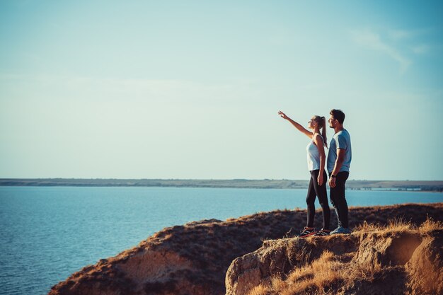 La joven pareja de pie en la cima de la montaña sobre el mar