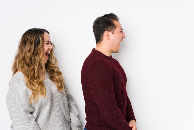 Joven pareja posando en una pared blanca gritando hacia un espacio de copia