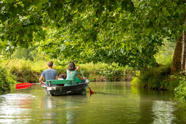 Una joven pareja remando el barco navegando entre La Garette y Coulon, Marais Poitevin la Venecia Verde, cerca de la ciudad de Niort, Francia