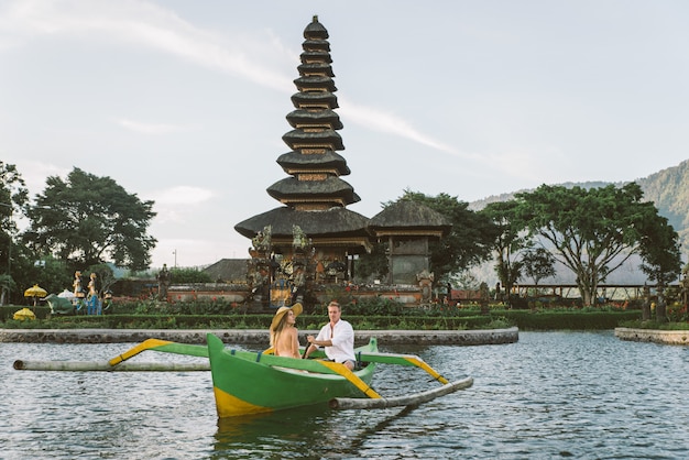 Joven pareja remando en un bote de madera en Pura Ulun Danu Bratan