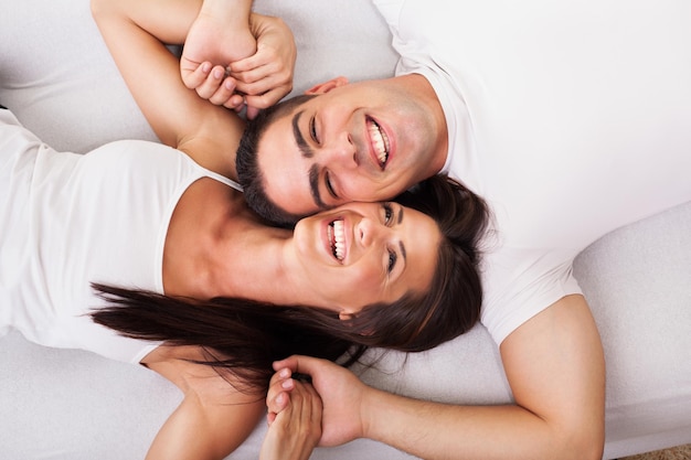 Joven pareja romántica acostada en la cama. Vista desde arriba.