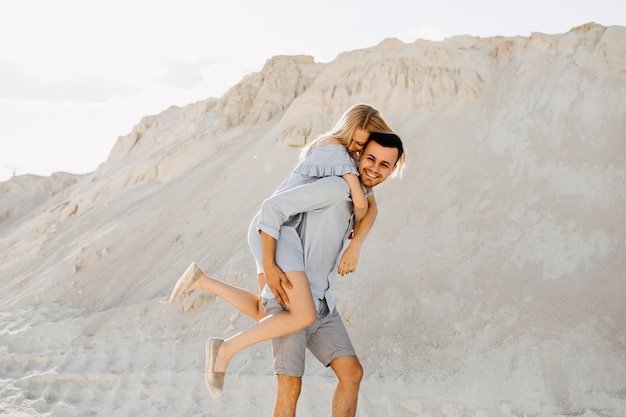 Joven pareja romántica al aire libre. Hombre dando un paseo a cuestas, ambos sonriendo.