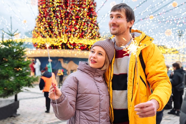 Una joven pareja romántica con bengalas se divierte en vacaciones al aire libre en invierno