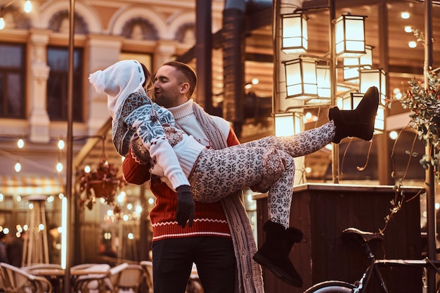 Joven pareja romántica disfrutando de pasar tiempo juntos en Navidad en la calle decorada con hermosas luces