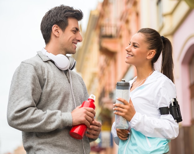 Joven pareja en ropa deportiva con botellas de agua.