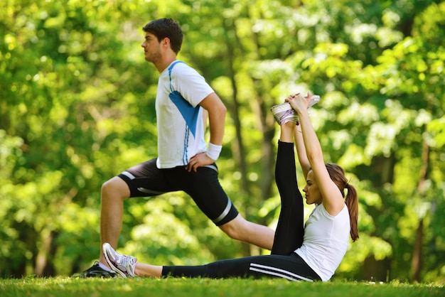 joven pareja de salud haciendo ejercicio de estiramiento relajándose y calentándose después de trotar y correr en el parque