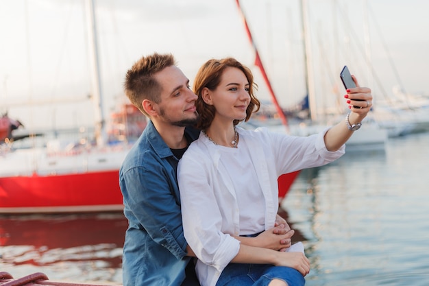 Joven pareja sonriente en el amor hace selfie retrato con teléfono. Concepto romántico