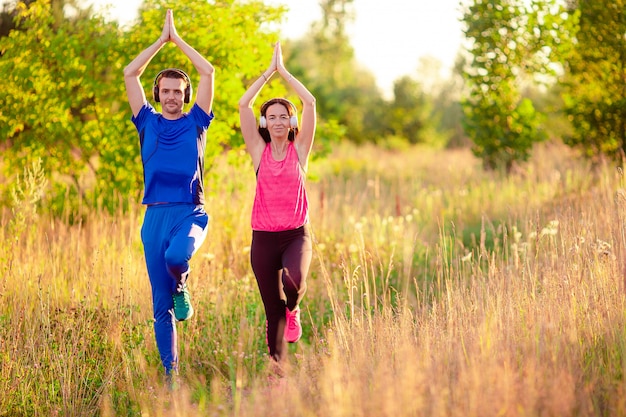 Joven pareja sonriente haciendo ejercicios deportivos al aire libre