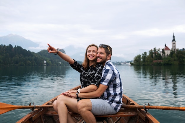 Joven pareja de turistas enamorados en barco de madera tradicional en el lago Bled, Eslovenia