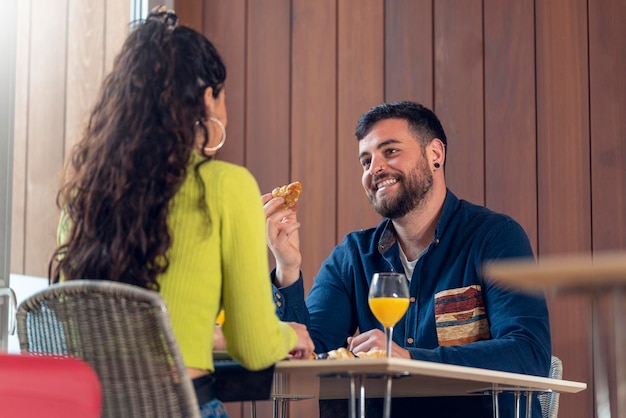 Joven pareja de turistas hablando y desayunando en el comedor de un hotel