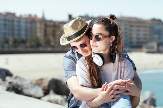 Joven pareja de turistas románticos abrazándose en la costa de una ciudad.