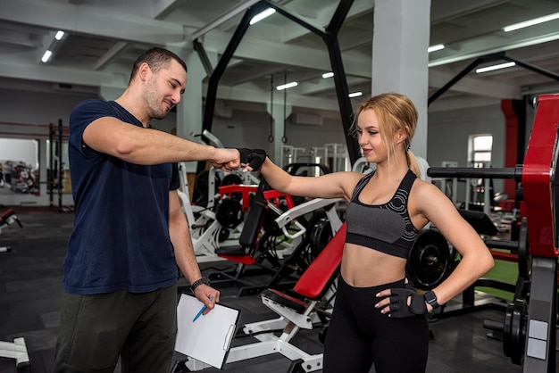 La joven participa en una máquina de entrenamiento con pesas en el gimnasio en el entrenador más prometedor de la ciudad El concepto de entrenamiento de fuerza en el gimnasio