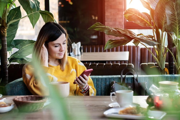 Una joven pasa el almuerzo en un café y habla por teléfono.