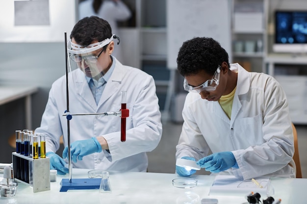 Joven pasante en laboratorio científico trabajando con equipos