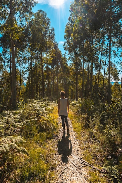 Una joven paseando por el camino entre árboles en el Parque Natural de Listorreta