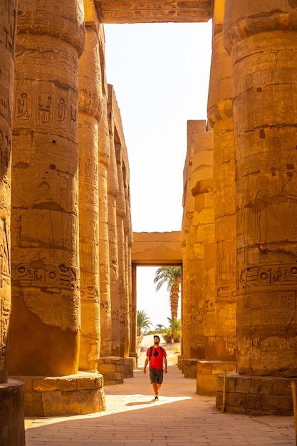 Joven paseando entre las columnas jeroglíficas del templo de Karnak, Egipto