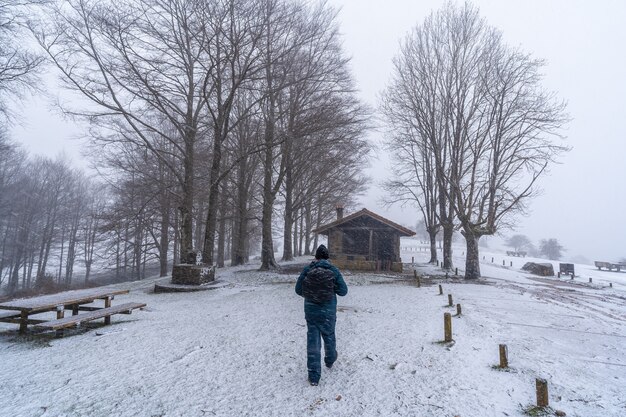 Un joven paseando junto al refugio del monte aizkorri en gipuzkoa. Paisaje nevado por nieves invernales