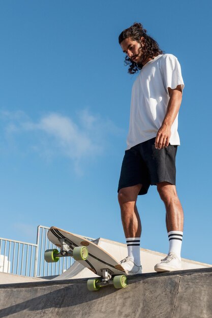 Joven patinador caucásico en el parque de patinaje listo para bajar por la rampa de patinaje