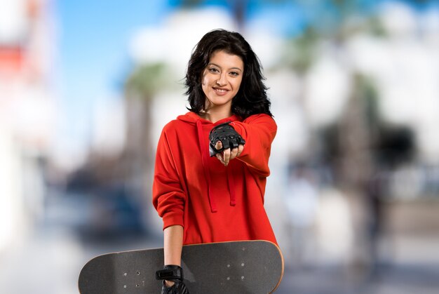 La joven patinadora te señala con una expresión de confianza al aire libre