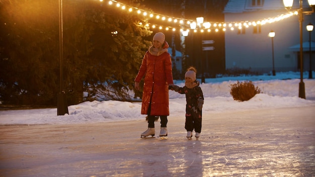 Una joven patinando en una pista de hielo pública con su hija
