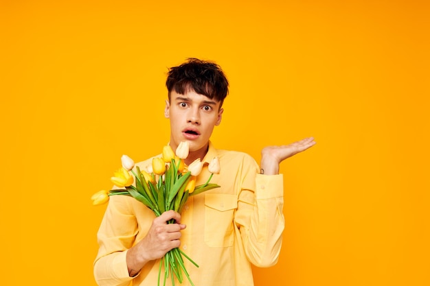 Un joven con un peinado de moda en camisas amarillas con flores de fondo amarillo inalterado