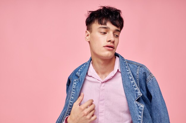 Un joven peinado de moda posando ropa chaqueta de mezclilla estilo moderno fondo rosa inalterado