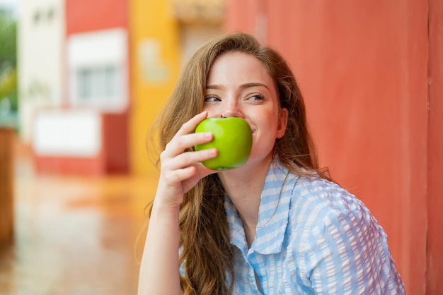 Joven pelirroja al aire libre sosteniendo una manzana