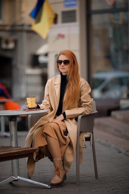 joven pelirroja bebiendo café en un café