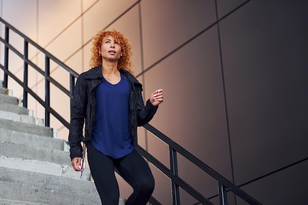 Joven pelirroja europea tiene caminar en las escaleras al aire libre