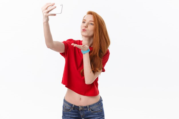 joven pelirroja feliz mujer aislada sobre fondo de pared blanca hacer selfie