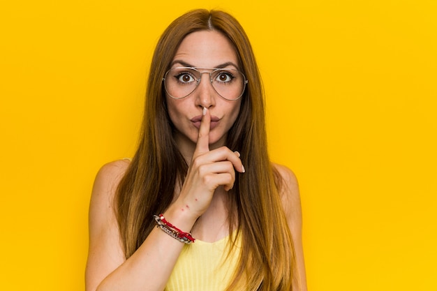 Joven pelirroja jengibre con pecosa guardando un secreto o pidiendo silencio.