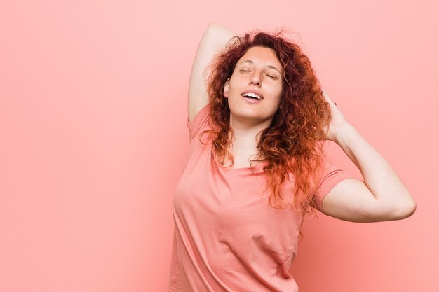 Joven pelirroja natural y auténtica mujer estirando los brazos, posición relajada.