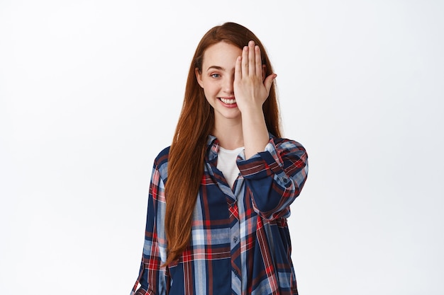 Joven pelirroja sonriente mujer con largo cabello rojo de pie en camisa a cuadros en blanco