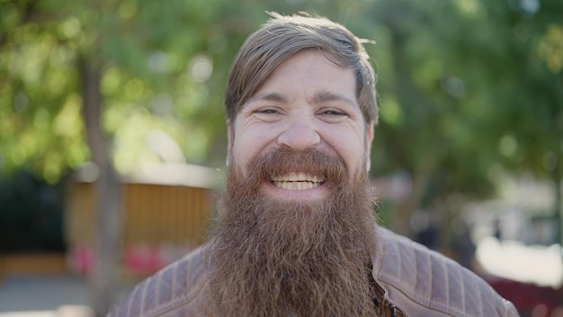 Joven pelirrojo sonriendo confiado de pie en el parque